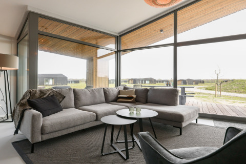 Moderne lodge-stue med store vinduer i Heerlijkheid Vlietenburg 1, med udsigt over naturen i Holland.