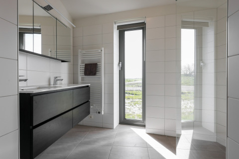 Moderne badeværelse i Heerlijkheid Vlietenburg 1 lodge i Holland, med store vinduer og sort møblement.