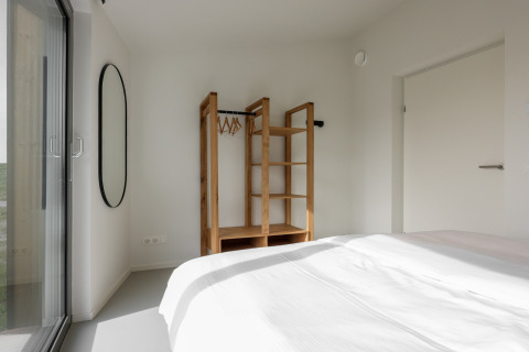 Minimalistisk soveværelse på Heerlijkheid Vlietenburg 1, Holland, med en åben garderobe og spejl.