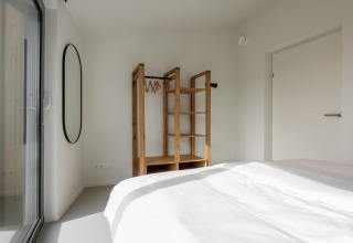 Minimalistisk soveværelse på Heerlijkheid Vlietenburg 1, Holland, med en åben garderobe og spejl.