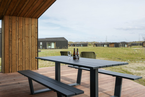 Udendørs spiseplads på Heerlijkheid Vlietenburg 1 lodge i Holland med udsigt over græs og hytter.