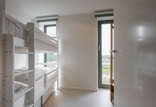 Lyst værelse med køjeseng og store vinduer på Heerlijkheid Vlietenburg 1 lodge i Holland.