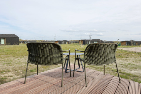 To flettede stole og et bord på en træterrasse med udsigt over Heerlijkheid Vlietenburg 1, Nederlandene.