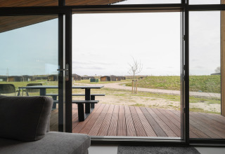 Udsigt fra en lodge med glasdør til terrasse og grønne områder i Heerlijkheid Vlietenburg, Holland.