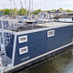 Husbåd ved navn Havenlodge N fortøjet ved Marina Parcs Naarden, Holland, omgivet af lystbåde.