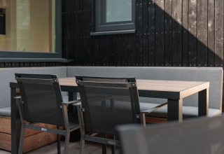 Udendørs siddeplads med moderne stole og bord ved lodge «Noordzee» Résidence De Banjaard 23, Holland.
