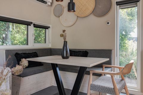 Moderne spiseplads med hjørnebænk, træbord, dekorative vægkurve og naturligt lys i lodge Noordzee.