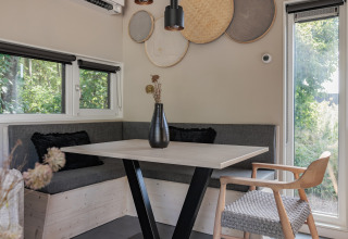 Moderne spiseplads med hjørnebænk, træbord, dekorative vægkurve og naturligt lys i lodge Noordzee.