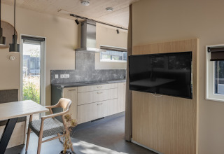 Moderne lodgekøkken og opholdsområde på Noordzee Résidence De Banjaard 23 i Holland med tv og spisebord.