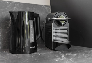 Sort elkedel og kaffemaskine på en marmorbordplade i lodge «Noordzee» Résidence De Banjaard 23, Holland.