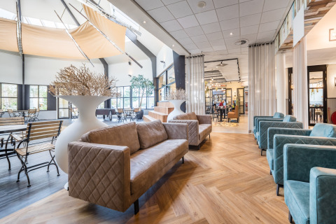 Bright, contemporary lounge area at a glamping accommodation with cozy sofas, tables, and large windows.