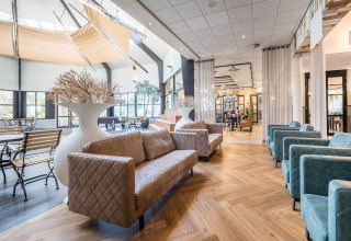 Bright, contemporary lounge area at a glamping accommodation with cozy sofas, tables, and large windows.