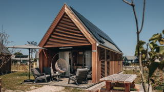 Moderne tiny house ved Beach Resort Nieuwvliet-Bad 17, med terrasse, solstole og solpaneler.
