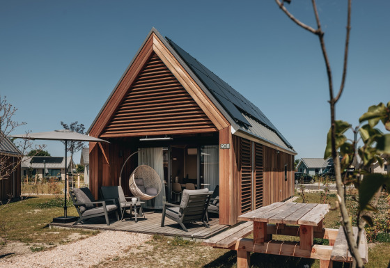 Moderne tiny house bij Beach Resort Nieuwvliet-Bad 17 met terras, zitstoelen en zonnepanelen.