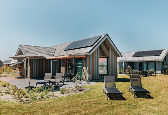 Buitenaanzicht van Beach Resort Nieuwvliet-Bad 16 met ligstoelen en zonnepanelen op het dak.