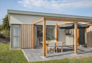 Udendørs terrasse ved Beach Resort Nieuwvliet-Bad 14 i Holland med spisebord, stole og parasol