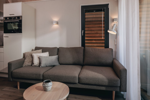 Gezellige zithoek in tiny house Beach Resort Nieuwvliet-Bad 17 met bank, kussens en salontafel.