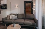Salon moderne du tiny house Beach Resort Nieuwvliet-Bad 17 avec canapé, coussins et table basse.