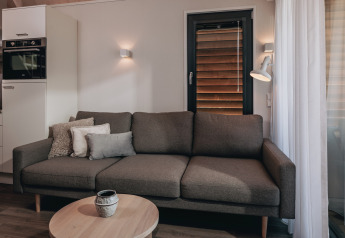 Salon moderne du tiny house Beach Resort Nieuwvliet-Bad 17 avec canapé, coussins et table basse.