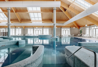 Indendørs swimmingpool i et glamping-ophold, med moderne spa-faciliteter og store vinduer.