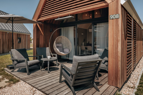 Udendørs terrasse med moderne møbler og hængestol ved Tiny House Beach Resort Nieuwvliet-Bad 17 i Holland.
