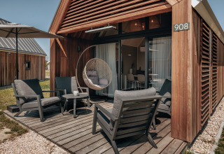 Gezellige veranda met stoelen en hangstoel aan tiny house Beach Resort Nieuwvliet-Bad 17 in Nederland.