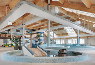 Zona de piscina cubierta con techo de madera y tobogán infantil en un alojamiento de glamping.