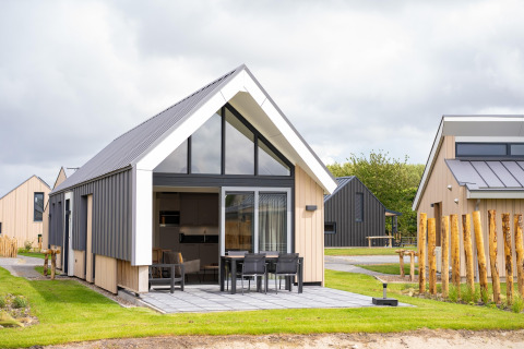 Lodge moderne au Holiday Park Zeebad 14 avec terrasse, grandes fenêtres et cadre verdoyant apaisant.