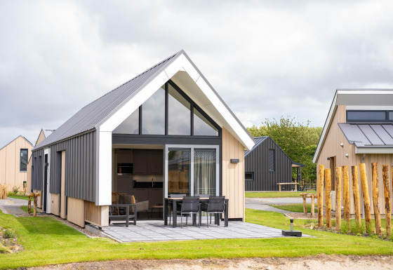 Lodge moderne au Holiday Park Zeebad 14 avec terrasse, grandes fenêtres et cadre verdoyant apaisant.