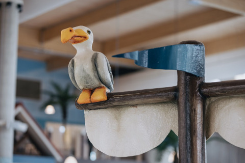 En sjov figur af en måge sidder på et indendørs skilt i et glamping-område fyldt med dekorationer.
