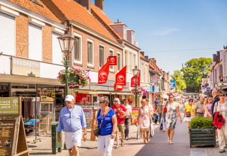 Folk spadserer i solskin gennem en livlig shoppinggade nær glampingindkvartering i Holland.