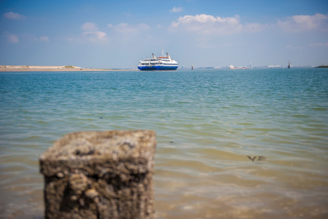 Vista desde un alojamiento glamping al mar con un ferry en la distancia bajo un cielo azul claro.