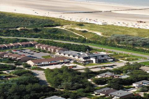 Luftfoto af glampingindkvartering nær stranden, omgivet af natur, ferieboliger og parkeringsplads.