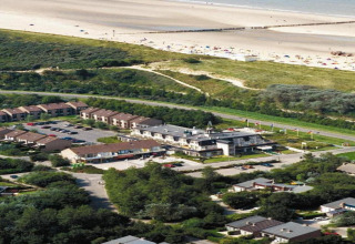 Luftfoto af glampingindkvartering nær stranden, omgivet af natur, ferieboliger og parkeringsplads.