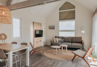Lys og moderne stue i Beach Resort Nieuwvliet-Bad 16 i Holland med sofa, stole og spisebord.