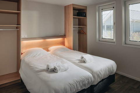 Moderne slaapkamer met twee eenpersoonsbedden, witte lakens en handdoeken in Beach Resort Nieuwvliet-Bad.
