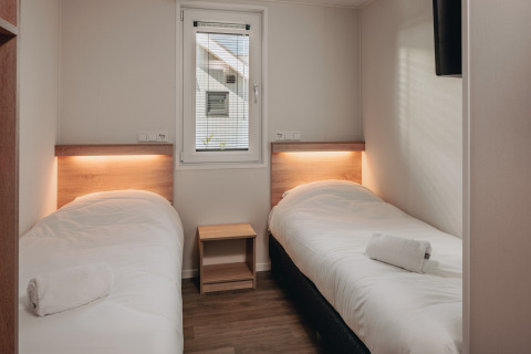 Twee eenpersoonsbedden met wit beddengoed op een kamer van Beach Resort Nieuwvliet-Bad 16 in Nederland.