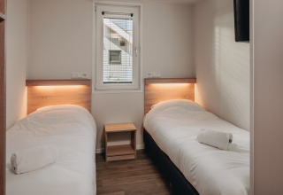 Twee eenpersoonsbedden met wit beddengoed op een kamer van Beach Resort Nieuwvliet-Bad 16 in Nederland.