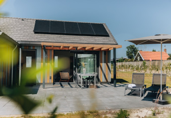 Terraza exterior del Beach Resort Nieuwvliet-Bad 16 en Países Bajos con paneles solares y muebles de jardín.