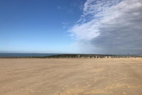 Strand med klart sand, blå himmel og delvist overskyet vejr ved Beach Resort Nieuwvliet-Bad 16, Holland.