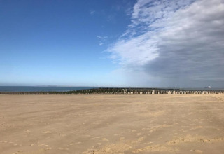 Strand med klart sand, blå himmel og delvist overskyet vejr ved Beach Resort Nieuwvliet-Bad 16, Holland.