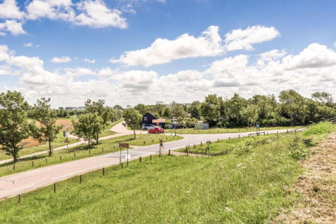 Udsigt over det landlige område nær Beach Resort Nieuwvliet-Bad 16 i Holland med grønne marker og vej.