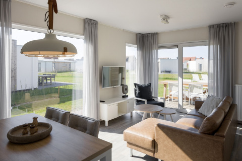 Lyst og moderne opholdsstue i en lodge på Beach Resort Nieuwvliet-Bad med adgang til terrasse og have.