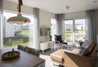 Lyst og moderne opholdsstue i en lodge på Beach Resort Nieuwvliet-Bad med adgang til terrasse og have.