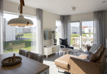 Sala de estar luminosa y moderna en una cabaña del Beach Resort Nieuwvliet-Bad con ventanales y terraza.