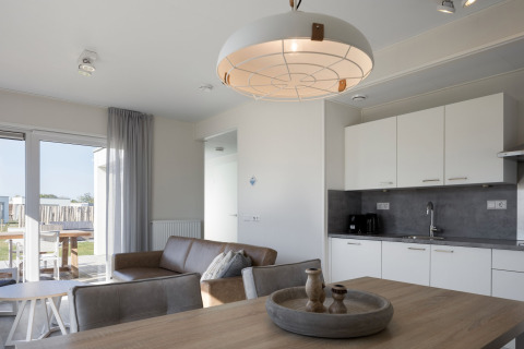 Moderne lodge-stue og køkken med minimalistisk indretning på Beach Resort Nieuwvliet-Bad i Holland.