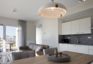 Moderne lodge-stue og køkken med minimalistisk indretning på Beach Resort Nieuwvliet-Bad i Holland.