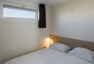 Lyst og enkelt værelse på Beach Resort Nieuwvliet-Bad 14 med to enkeltsenge og lille vindue.