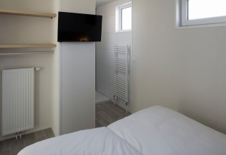 Moderne lodge med TV, radiator, hylder og soveområde på Beach Resort Nieuwvliet-Bad 14 i Holland.
