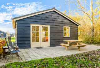 Foran Holiday Home «5 Aarde Green Camping Lage Zwaluwe» i Holland ses en hytte med terrasse og bænk.